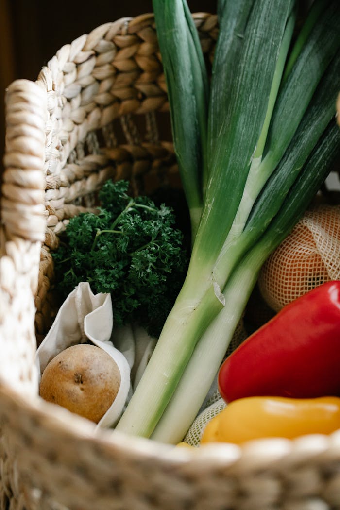 A collection of fresh organic vegetables like leek, pepper, and potato in a wicker basket, perfect for cooking inspiration.